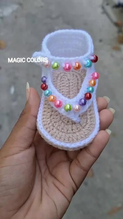 someone is holding up a crocheted slipper with colorful beads on the bottom