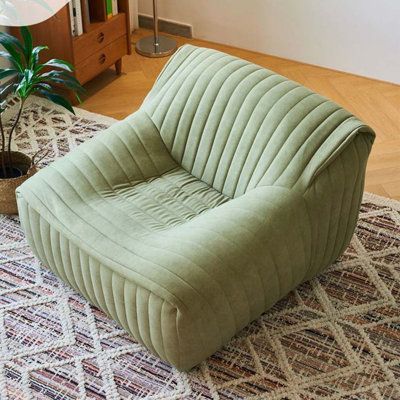 a green chair sitting on top of a rug next to a potted plant