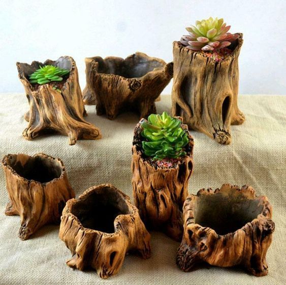 there are seven pieces of wood that have been carved to look like stumps with plants in them