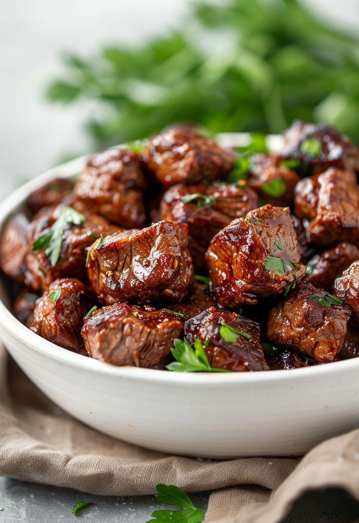 a white bowl filled with meat and garnished with parsley on the side