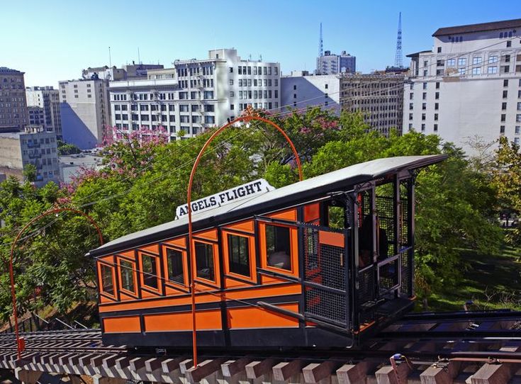 an orange and black trolley car traveling through the city