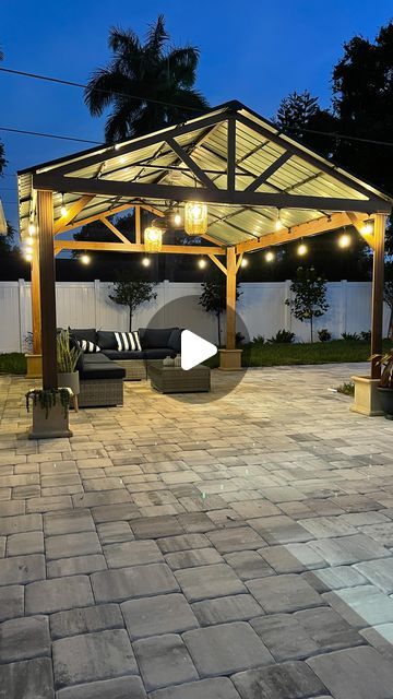 a gazebo with lights on it sitting in the middle of a patio at night