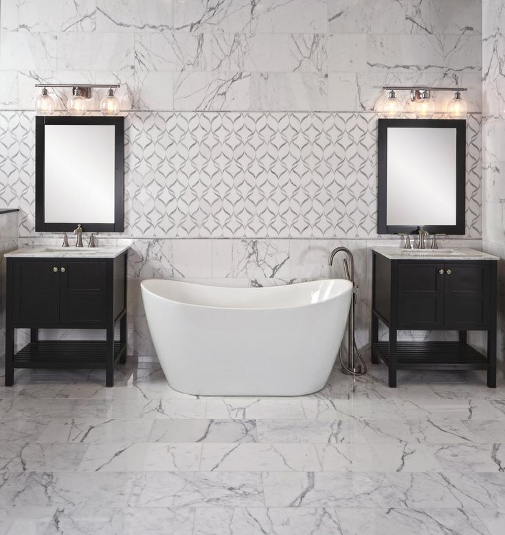 a white bath tub sitting next to two sinks in a bathroom under mirrors and lights