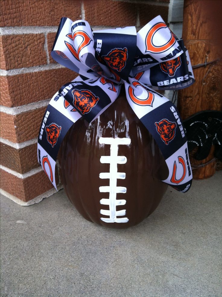 a football ornament with a bow on the front of it, tied to a brick wall