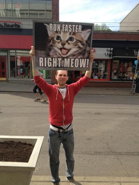 a man holding up a sign that says run faster right meow in front of him