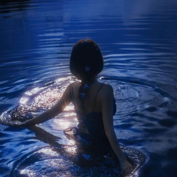 a woman sitting in the water with her hands behind her back