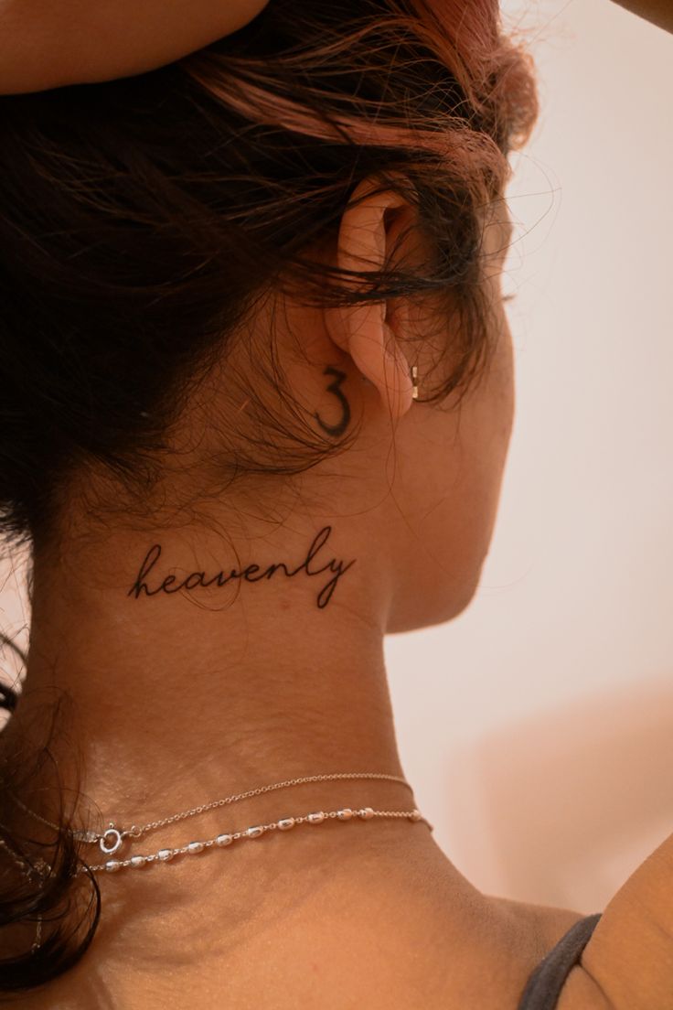 the back of a woman's neck has a tattoo that says heavenly on it