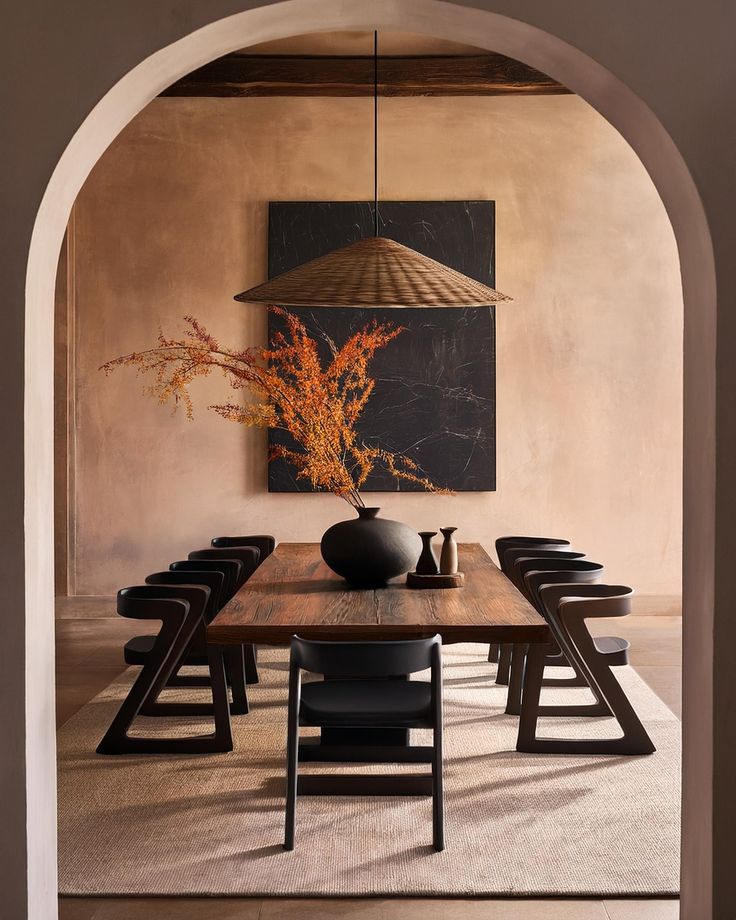 a dining room table with chairs and a vase on the table in front of an archway