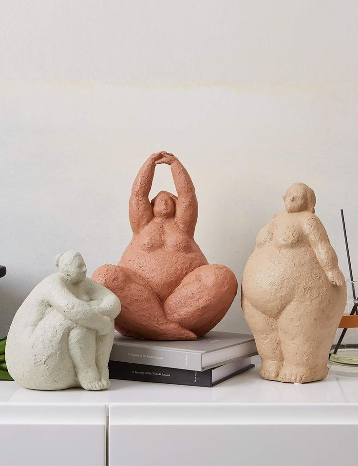 three different colored sculptures sitting on top of a white shelf next to a planter