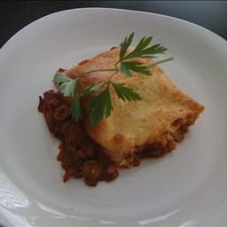 a white plate topped with a piece of pie covered in meat and veggies