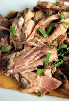 a white plate topped with meat covered in sauce and garnished with green onions