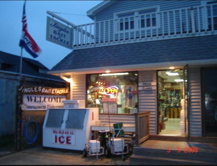 an ice cream shop is lit up at night with the american flag in the background