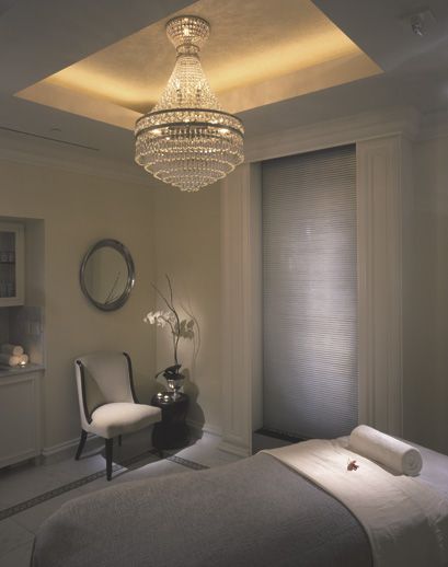 a bed room with a neatly made bed and a chandelier hanging from the ceiling