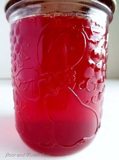 a jar filled with red liquid sitting on top of a white table next to a wall