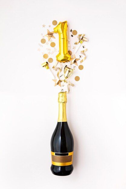 a bottle filled with gold foil and confetti on top of a white table