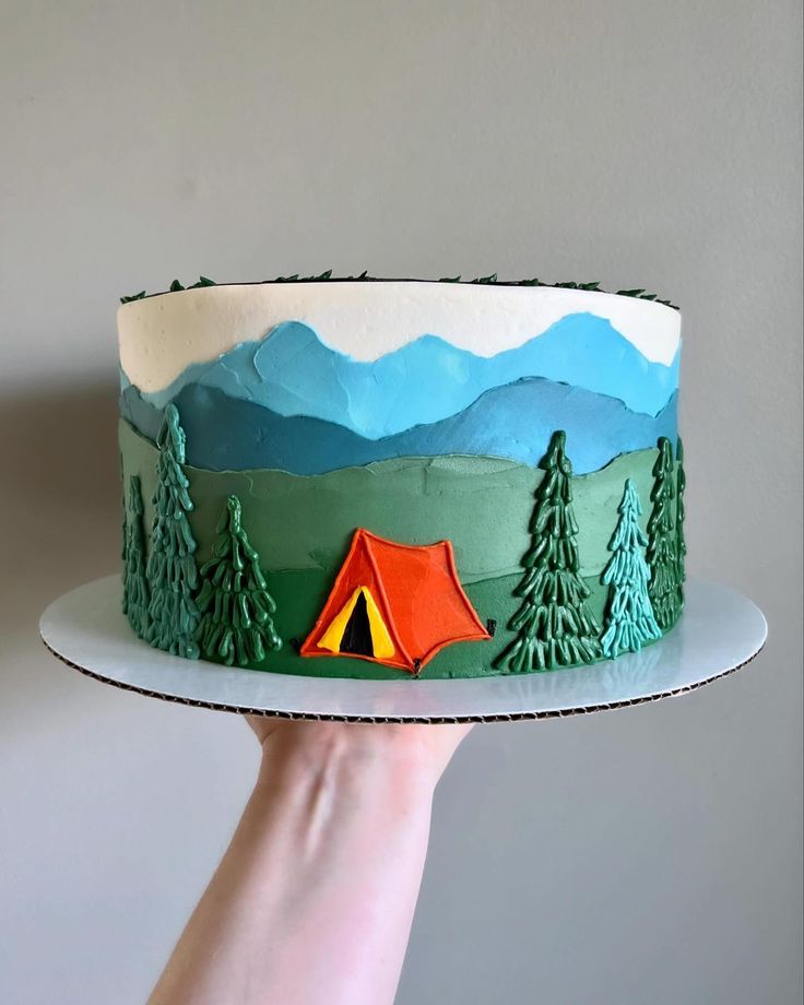 a hand holding a cake with a tent on it