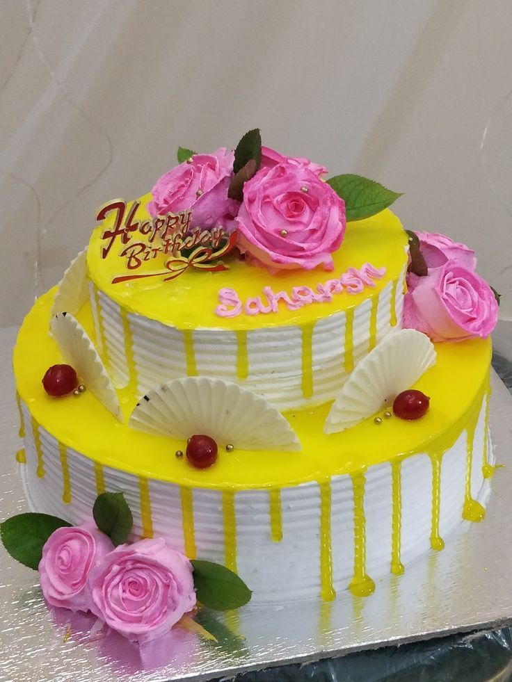 a yellow and white cake with pink roses on top