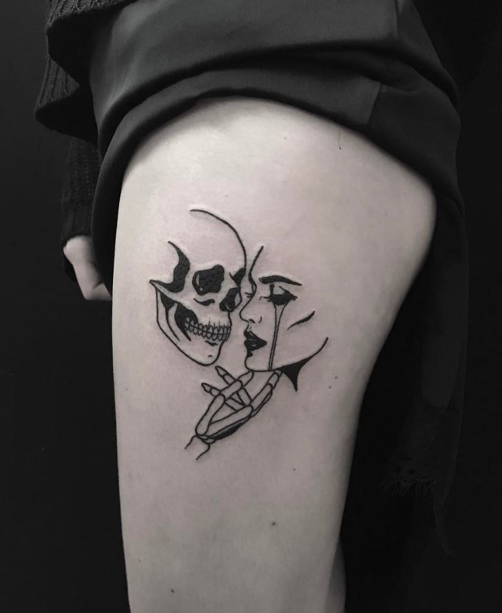 a woman's thigh with a skull and knife tattoo on her left side leg