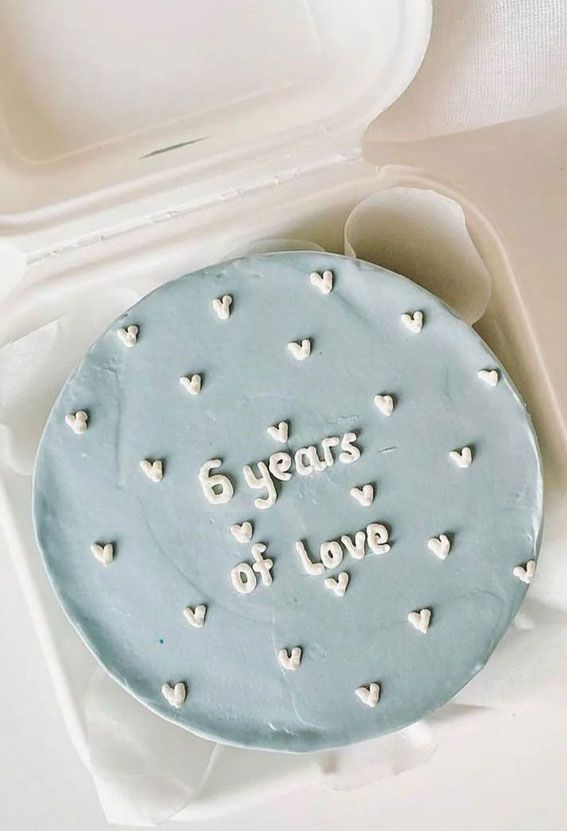 a blue cake with white hearts on it in a plastic container next to an open box