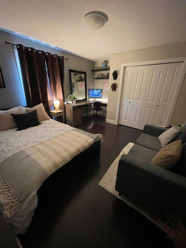 a bedroom with a bed, couch and desk in it's center area next to a doorway