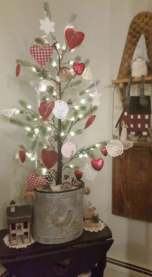 a small christmas tree in a tin can with hearts on it's branches and lights