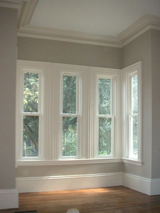 an empty room with three windows and hard wood flooring