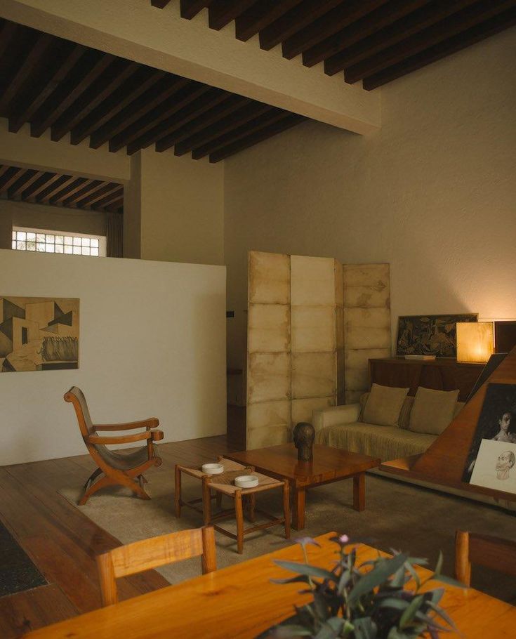 a living room filled with furniture and a wooden table in front of a white wall