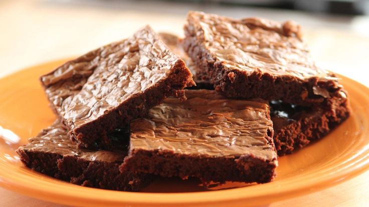 brownies with chocolate frosting on an orange plate