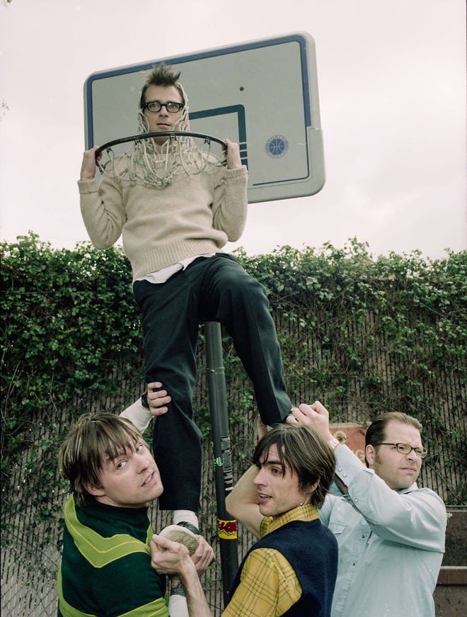 three young men are hanging upside down on a basketball hoop and posing for the camera