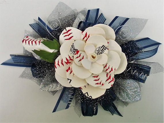 a baseball themed corsage with blue and white ribbons on the front, attached to a wall