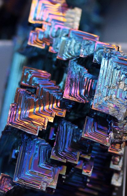 some very pretty colorful glass blocks on a table top with the reflection of them in it