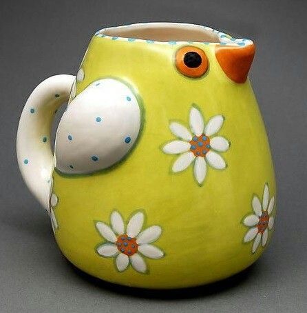 a yellow and white bird shaped vase with daisies on it's side, sitting on a gray surface