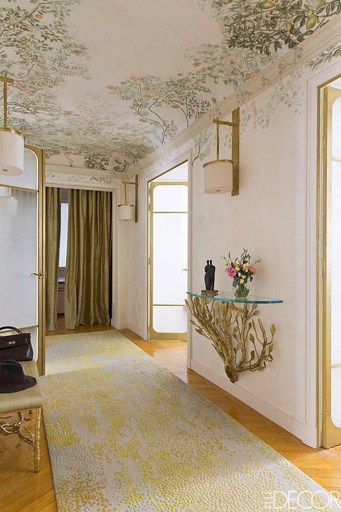 a living room filled with furniture and walls covered in floral wallpaper, along with a glass top coffee table