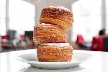 three donuts stacked on top of each other on a white plate with pink icing