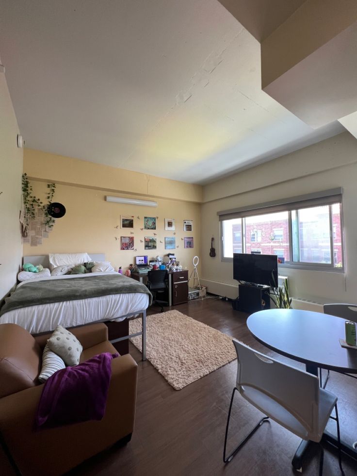 a bedroom with a bed, desk and chair in it next to a tv on the wall