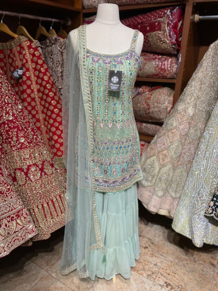 Sage green beautifully intricate with contrasting light pink, purple resham thread floral embroidery and highlighted in zari and stone work spaghetti strap kurta. Completed look with sharara and net dupatta. Fabric: Net Size: Regular (38-40) Ready to Ship! Designer Pista Green Sharara With Dori Work, Pista Green Sharara With Dabka Work And Traditional Drape, Pista Green Sharara With Dabka Work, Designer Green Palazzo Set With Intricate Embroidery, Festive Sleeveless Sharara With Dabka Work, Pista Green Chinon Sharara For Diwali, Designer Pista Green Sharara For Festivals, Pista Green Chinon Sharara With Traditional Drape, Anarkali Pista Green Sharara With Mirror Work