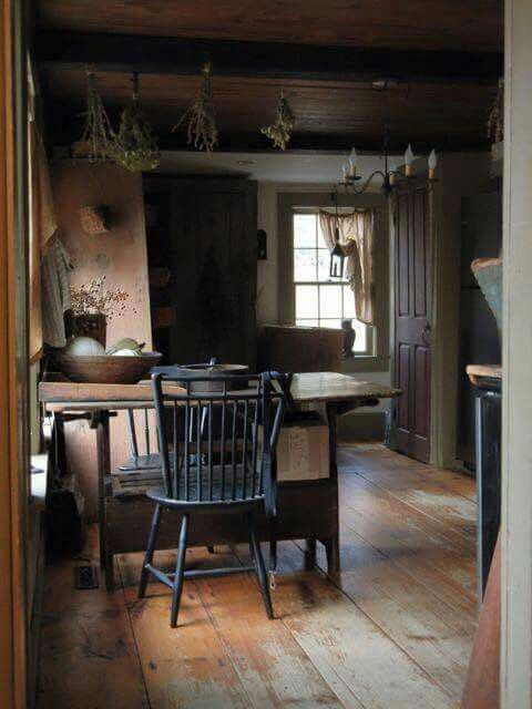 an old fashioned kitchen with wooden flooring and table in the center, looking into the dining room