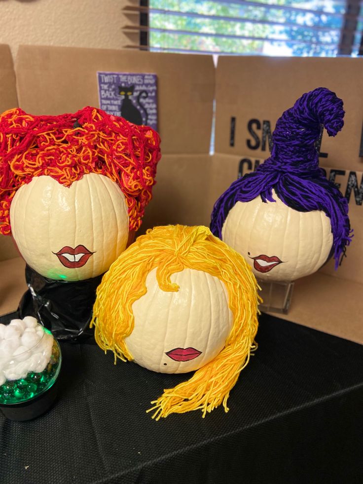 three pumpkins decorated to look like wigs and hair are sitting on a table