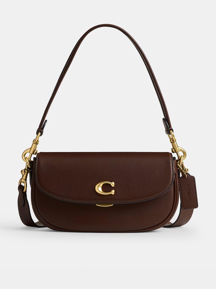 COACH Emmy 23 Glovetanned Leather Saddle BagSize & FitDimensions: Height: 13.5cm x Width: 23cm x Depth: 5cmHandle drop: 21cm Strap drop: 54cm DetailsEmmy 23 Glovetanned Leather Saddle Bag by CoachBrown Small but mighty, the Emmy is a chic, compact saddle bag that's perfect for days where you only need your essentials - wear snug on the shoulder or style across the body for effortless hands-free appeal Roomy enough to store your phone, keys, a lip balm and a small purse Crafted from buttery soft glovetanned leatherSignature C logo to the front Flap closure with a clasp fastening Includes a short removable handle and a detachable long shoulder strap for versatile stylingGold-tone metal hardware throughout Internal slip and zip pockets Material & Care Purse Crafts, Leather Saddle Bags, C Logo, Signature Hardware, Saddle Bag, Small Purse, Big Deal, Small Bag, Saddle Bags