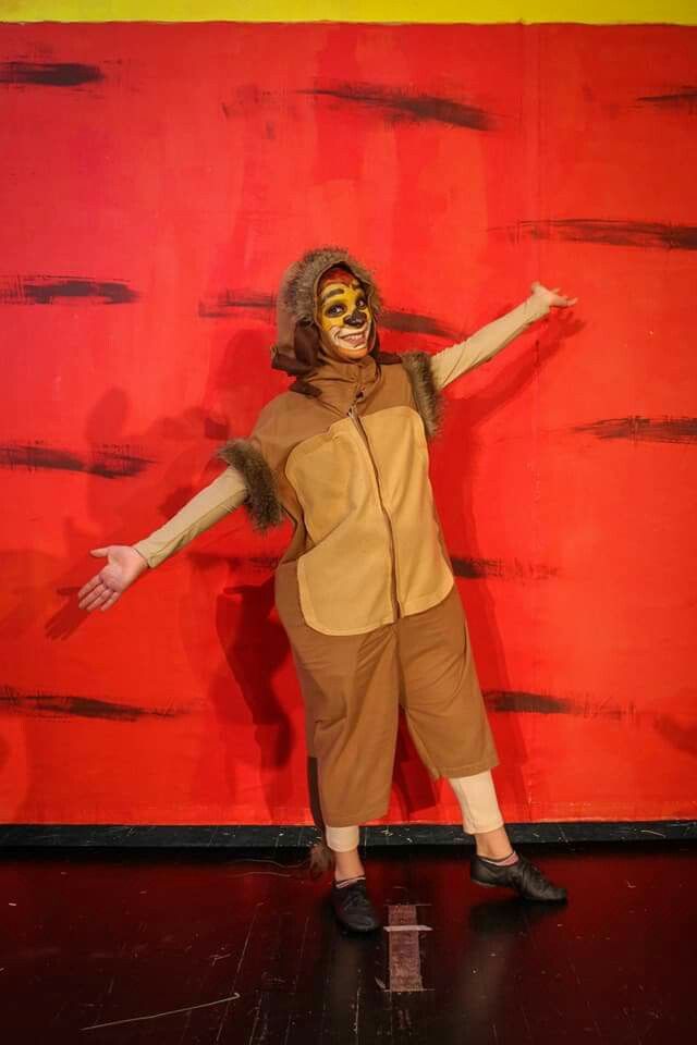 a person in a lion costume standing on a stage with their arms out and hands outstretched