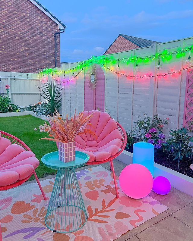 an outdoor patio with pink furniture and string lights