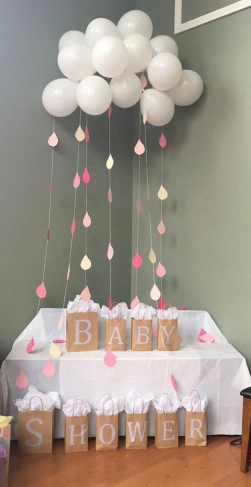 baby shower decorations with balloons hanging from the ceiling and paper bags in front of them