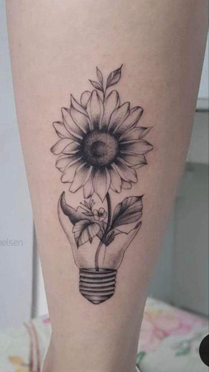 a tattoo with a light bulb and sunflower on it's thigh, in black and white