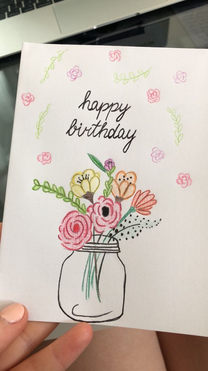 a person holding up a birthday card with flowers in a mason jar