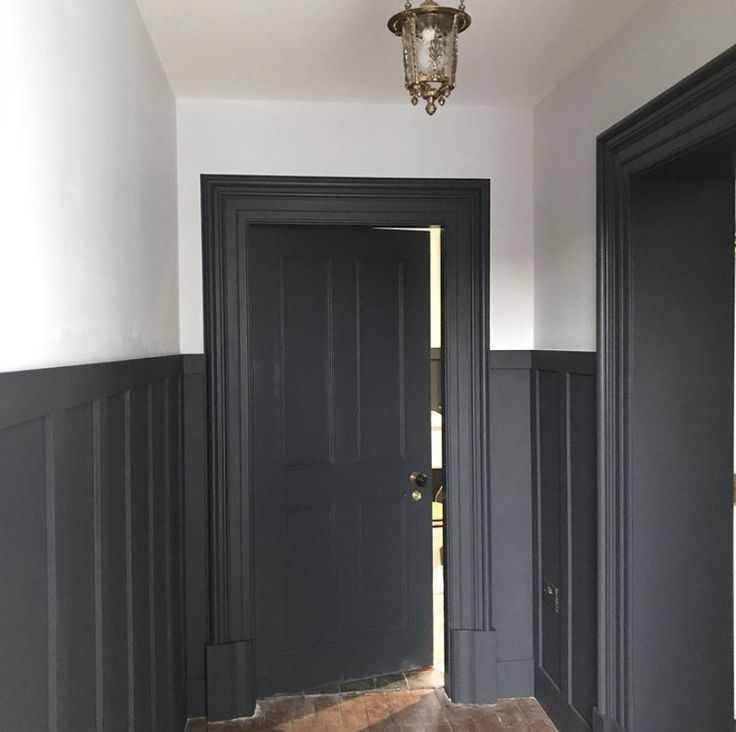 an empty hallway with two black doors and a chandelier