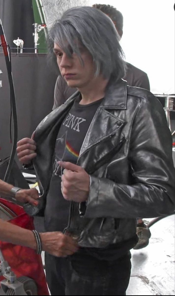 a man with grey hair wearing a black leather jacket and standing next to a woman