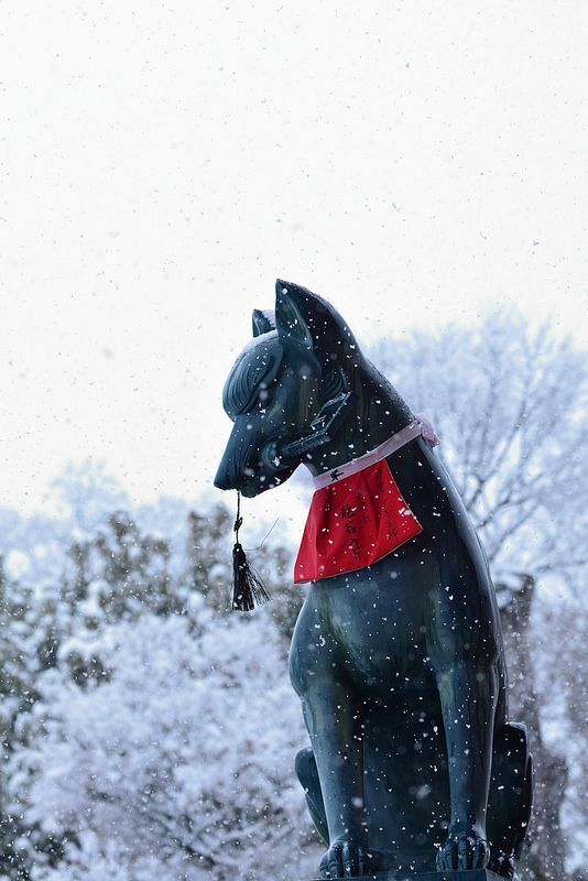 a black cat statue sitting in the snow