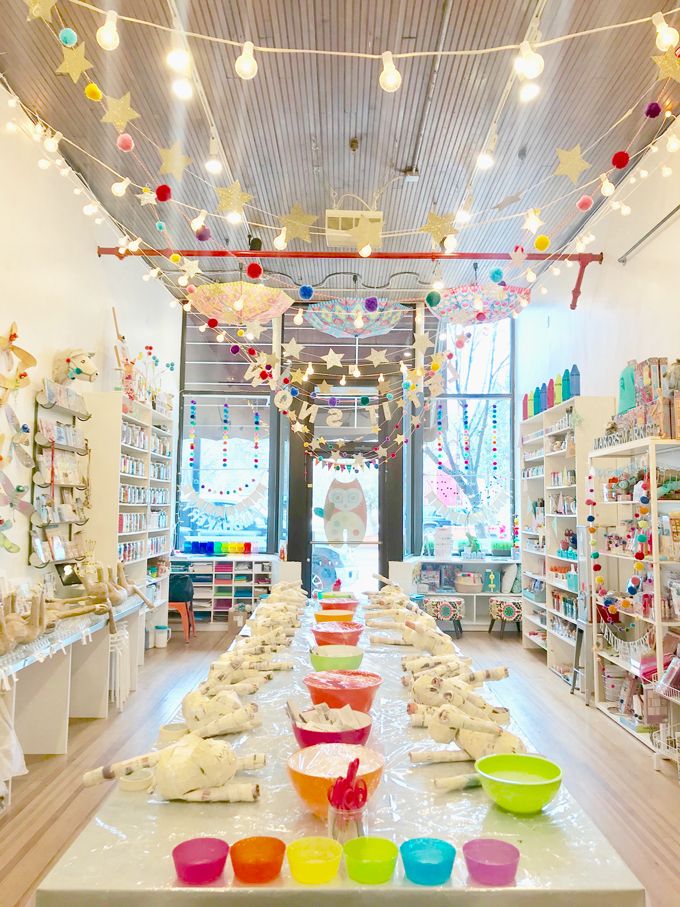 there are many bowls on the table in this store that is decorated with lights and decorations