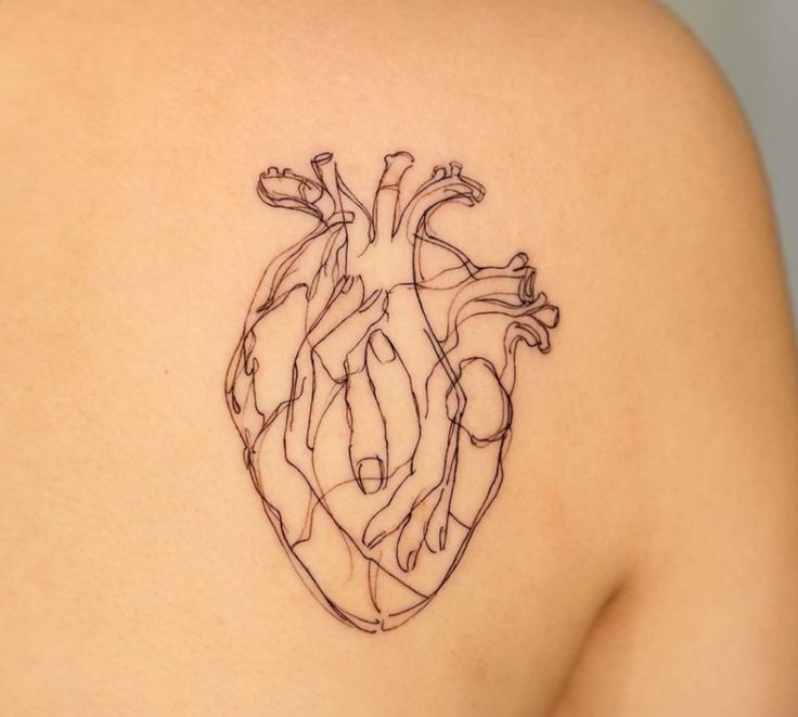 a heart tattoo on the back of a woman's shoulder