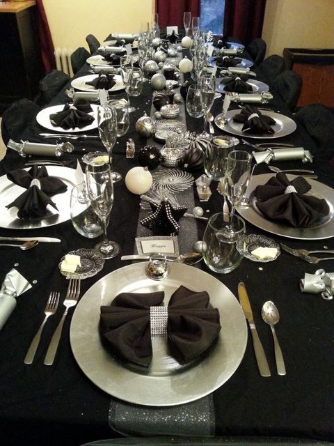 the table is set with black and white plates, silverware, and napkins